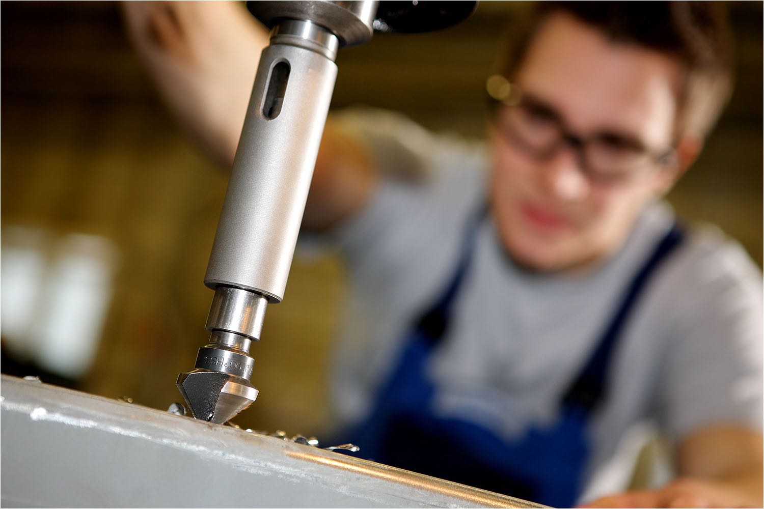  Industriefotografie. Zum Handwerk zählt die Ausbildung. Junger Lehrling beim Bohren seines Gesellenstückes. Aufnahme für einen Imagekatalog fotografiert mit digitaler Technik durch Fotostudio Riethausen.  