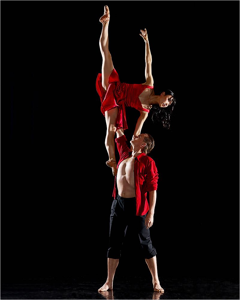  Tanzfotografie. Tanzpaar im Studio im Spagat vor dunklem Hintergrund. Balanceakt aufgenommen mit Studioblitzanlage und Mittelformat digital. Copyright by Fotostudio Jörg Riethausen 