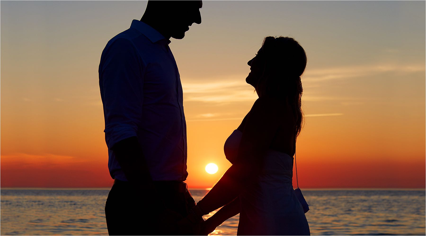  Ein unvergesslicher Augenblick am ende eines schönen Tages. Das Brautpaar vor der untergehenden Sonne am Meer. Copyright by Fotostudio Jörg Riethausen 