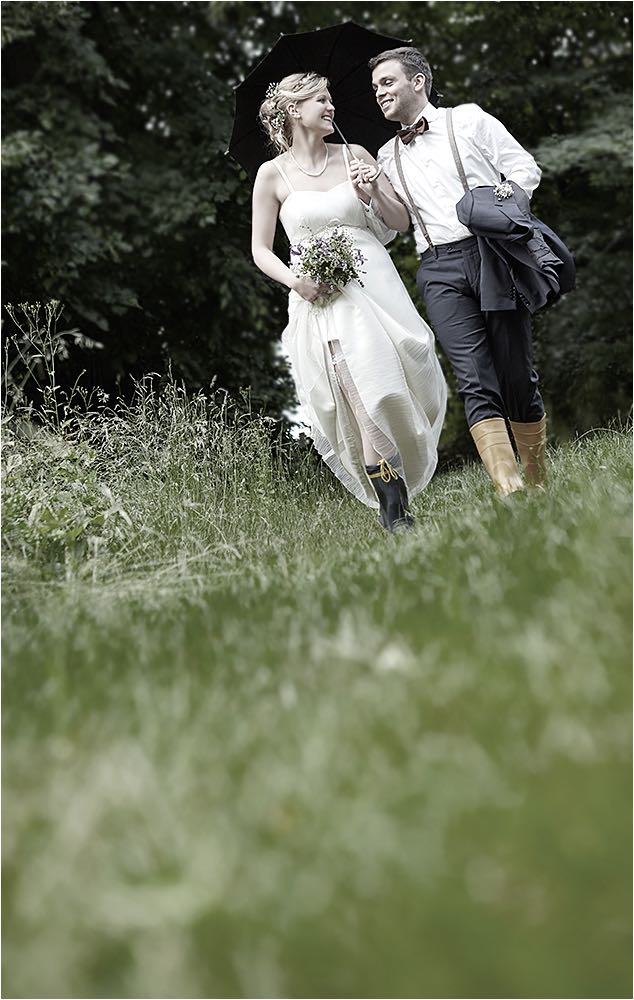  Das Brautpaar in Gummistiefeln durch die nasse Wiese wandernd. Aufgenommen mit digitaler Kleinbildtechnik und vorhandenem Licht. Copyright by Fotostudio Jörg Riethausen 