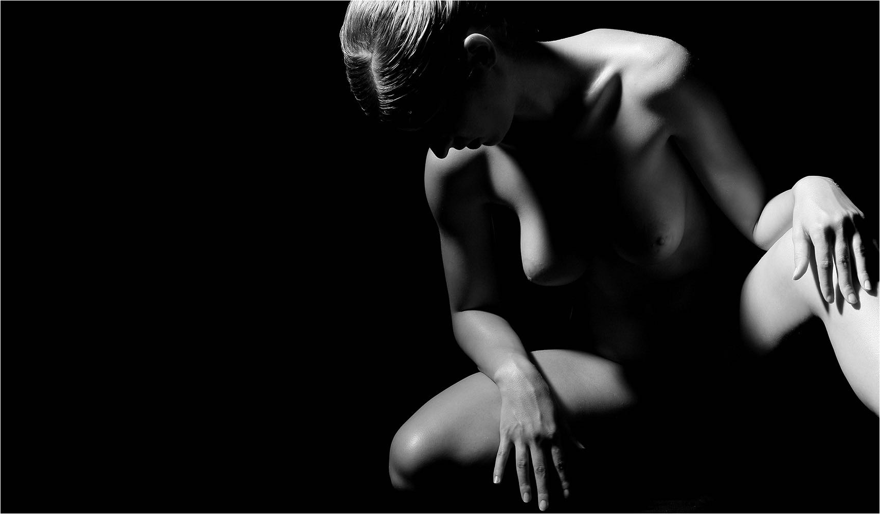  Versteckter Akt einer jungen Frau vornüber gebeugt und sitzend mit schwarzem Hintergrund als LowKey. Copyright by Fotostudio Jörg Riethausen 