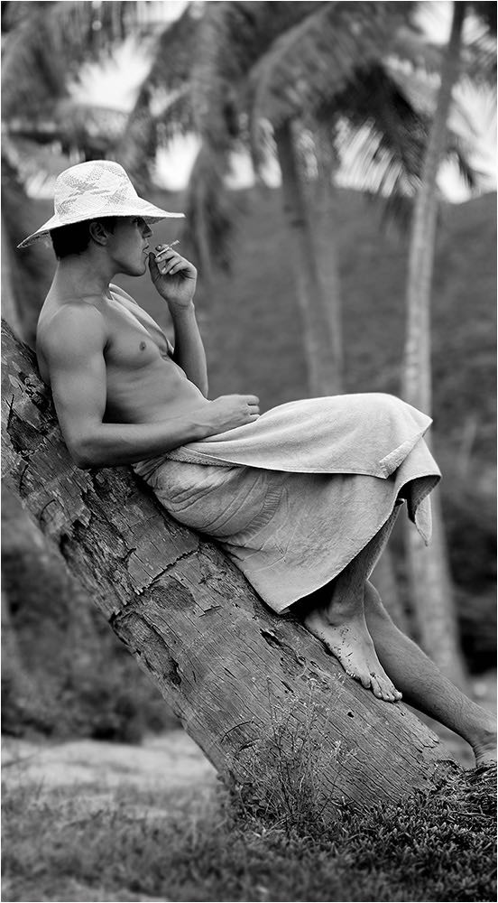  Verdeckter Akt eines jungen Mannes mit Hut und Zigarette an eine Palme gelehnt auf einer karibischen Insel. Kleinbildkamera und available Light. Copyright by Fotostudio Jörg Riethausen 