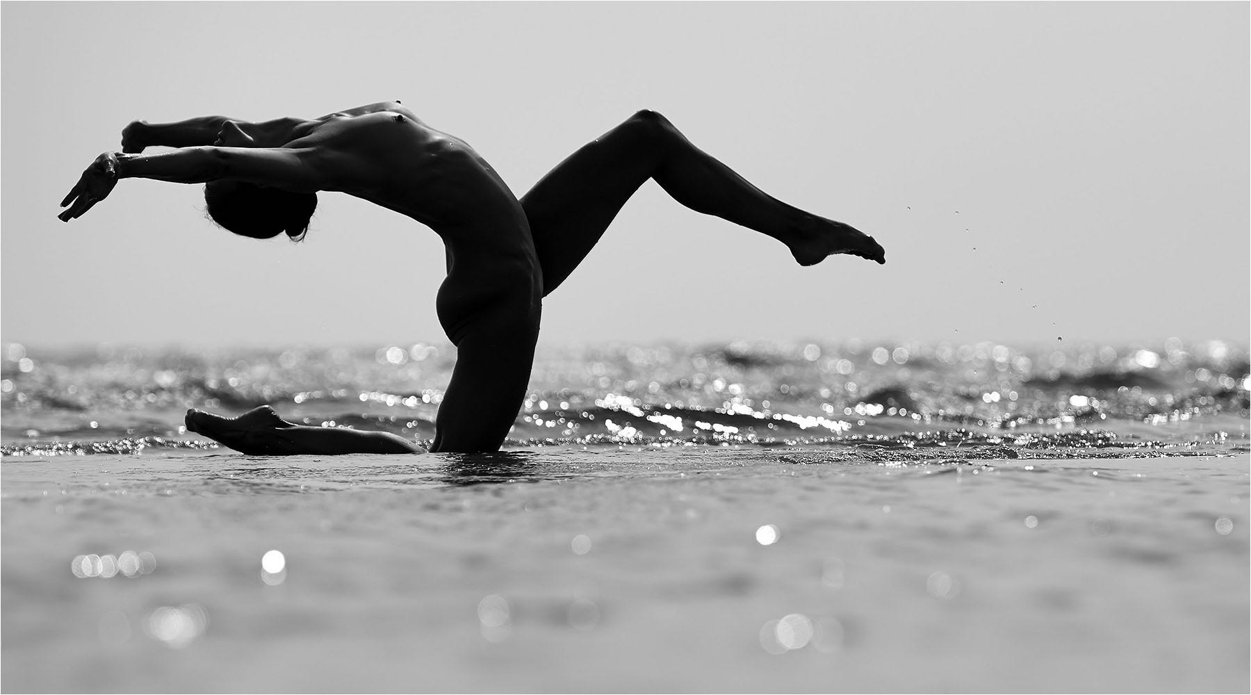  Tänzerischer Akt als Silhouette einer Frau im Meer knieend. Aufgenommen bei available Light und mit der Digitalkamera Kleinbild. Copyright by Fotostudio Jörg Riethausen 