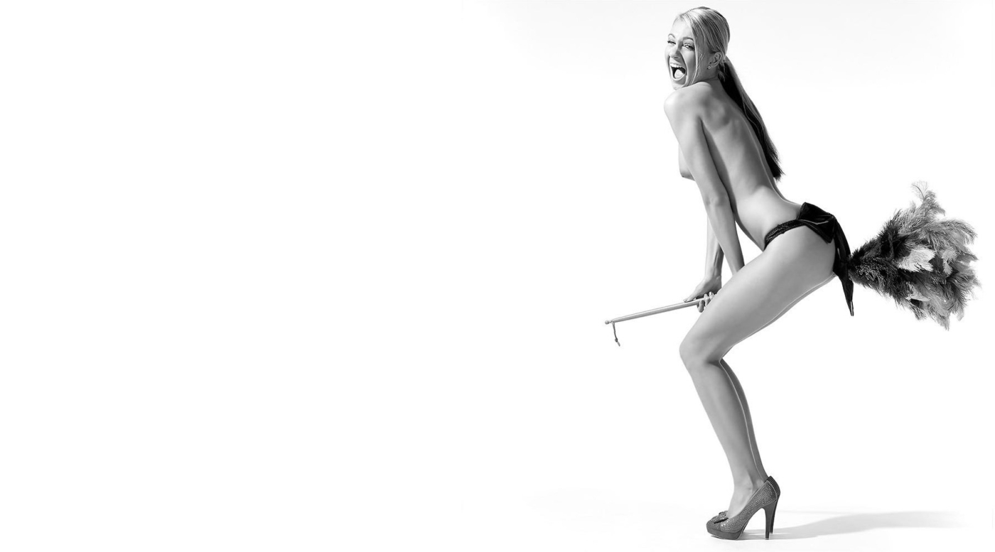 Witziger Halbakt einer Frau die auf einem Besen als Hexe reitet im weissen Studio