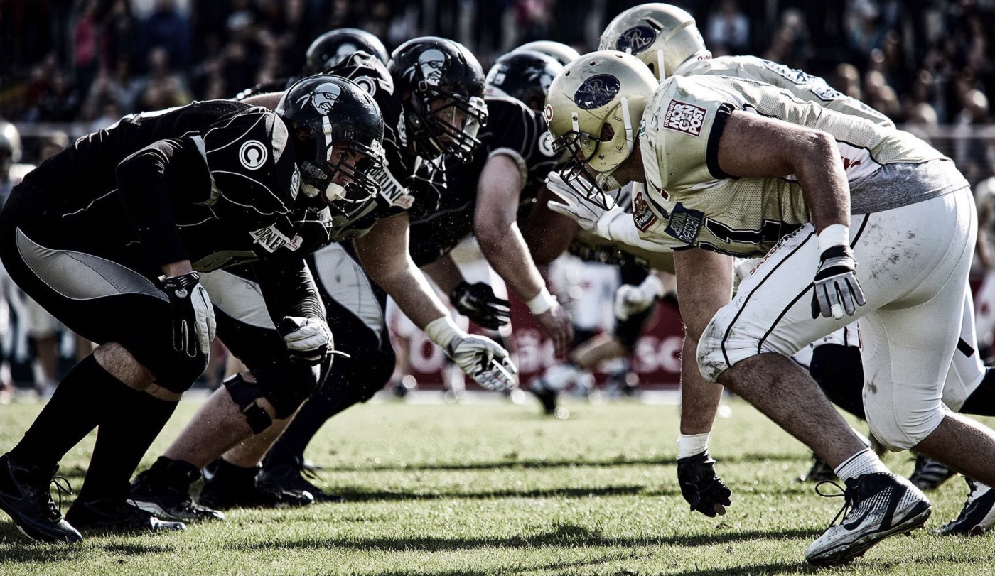 Startszene beim American Football. Männer Kopf an Kopf