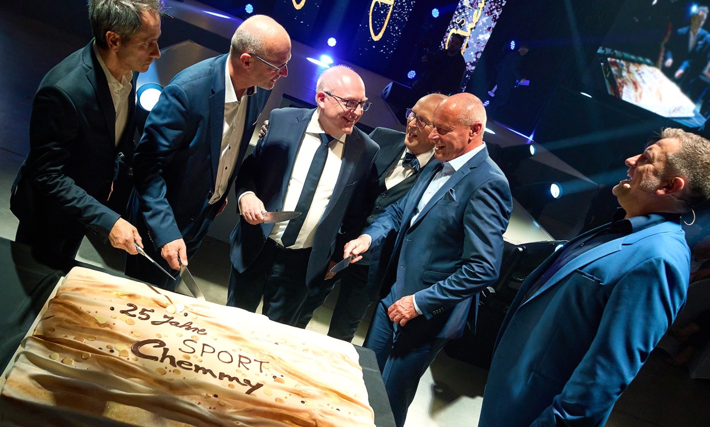 6 Geschäftsmänner im Anzug beim Torte anschneiden während einer Sportler Preisverleihung