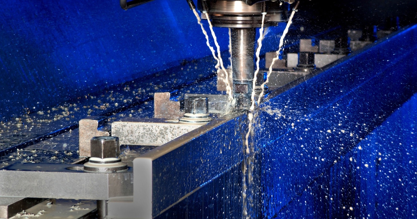 Metallbearbeitung. Maschinenfräse im Einsatz in blauem Licht und weisem Kühlmittel Strahl