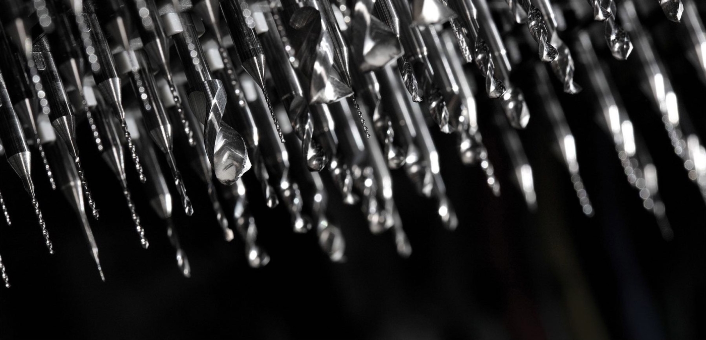 Verschiedenste Bohrer nebeneinander hängend vor schwarzem Hintergrund