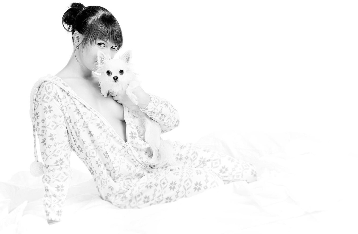 Kuscheliger Hund mit verträumter Besitzerin im Schlafanzug im weissen Studio